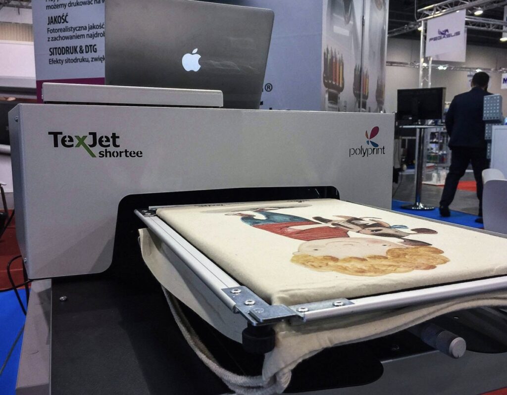 Impresora DTG compacta Polyprint TexJet Shortee imprimiendo en una feria del sector